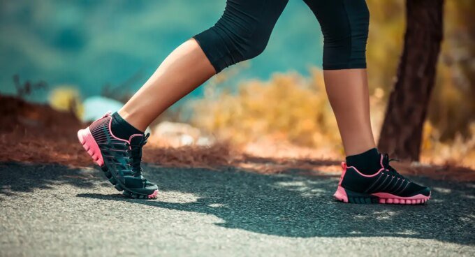 Personne souriante faisant du sport en extérieur au lever du soleil, symbolisant la joie et la vitalité de la reprise sportive.