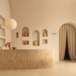 Interior view of Sana Skin Studio in Wynwood, showcasing its high ceilings, arched doorways, and a circular illuminated feature with a soothing beige palette.