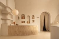 Interior view of Sana Skin Studio in Wynwood, showcasing its high ceilings, arched doorways, and a circular illuminated feature with a soothing beige palette.