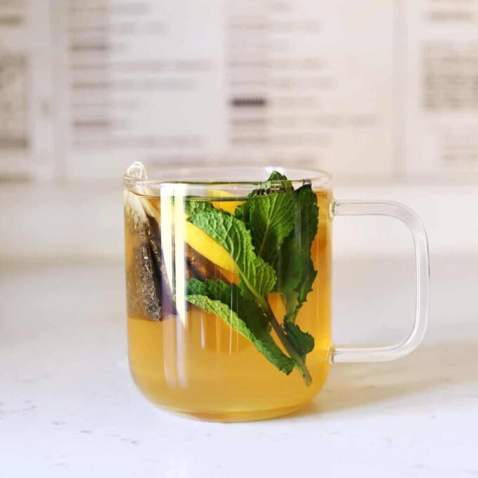 A warm mug of Starbucks Medicine Ball tea with lemon slices and mint leaves