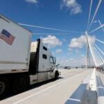 A truck crosses the Gordie Howe International Bridge, symbolizing the flow of trade between Windsor, Ontario, and Detroit, Michigan, amidst escalating US-Canada trade tensions.