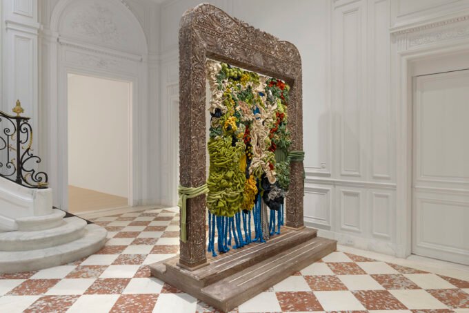 Wangari Mathenge's 'Re-membering XIII (May the Wind Be Always at Your Back)' showing figures in a richly layered domestic interior.