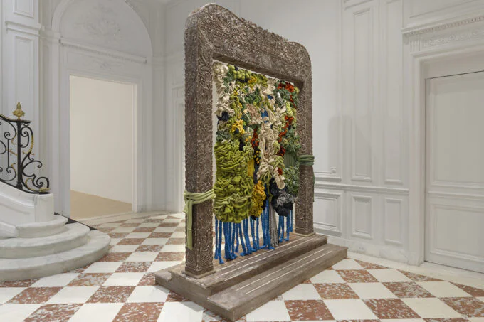 Wangari Mathenge's 'Re-membering XIII (May the Wind Be Always at Your Back)' showing figures in a richly layered domestic interior.