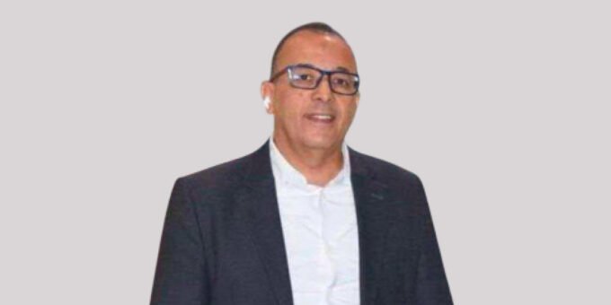 Amine Amanatoullah, Secrétaire général de la FIFEL, s'exprimant avec gravité sur les défis climatiques et hydriques qui menacent l'agriculture marocaine, notamment les cultures maraîchères du Souss-Massa, avec des serres en arrière-plan sous un ciel potentiellement nuageux ou ensoleillé.