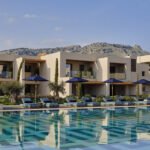 Exterior view of Amoh Resort in Rhodes, showcasing its low-rise stone architecture blending seamlessly with the coastal landscape.