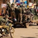 Rebelles de l'AFC/M23 entrant dans la ville de Bukavu, le 16 février 2025, montrant des hommes armés en tenue militaire marchant dans une rue de la ville.