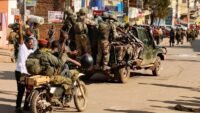Rebelles de l'AFC/M23 entrant dans la ville de Bukavu, le 16 février 2025, montrant des hommes armés en tenue militaire marchant dans une rue de la ville.