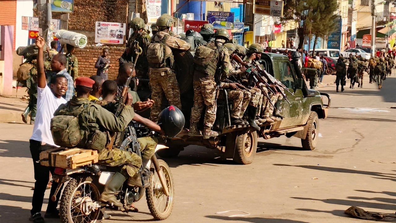 Rebelles de l'AFC/M23 entrant dans la ville de Bukavu, le 16 février 2025, montrant des hommes armés en tenue militaire marchant dans une rue de la ville.