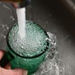 A sleek countertop water filter next to a kitchen sink, providing clean drinking water.