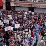 متظاهرون تونسيون يحملون الأعلام الوطنية ولافتات تطالب بالديمقراطية والحريات في شوارع تونس العاصمة.