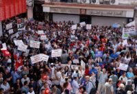 متظاهرون تونسيون يحملون الأعلام الوطنية ولافتات تطالب بالديمقراطية والحريات في شوارع تونس العاصمة.