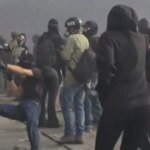 صورة لمظاهرات ليلية في إحدى المدن الفرنسية تظهر حشوداً ودخاناً في الخلفية، مع وجود قوات الأمن.