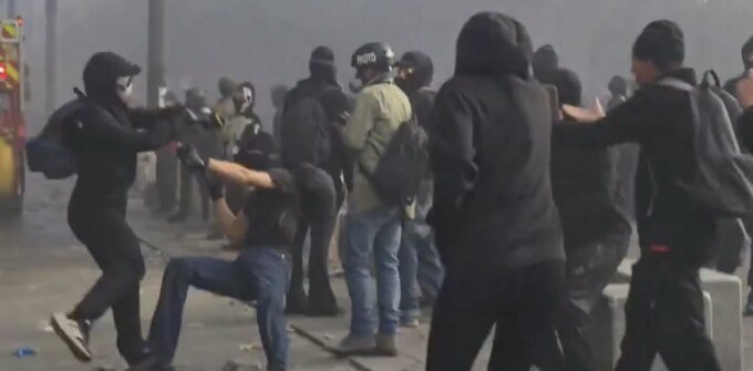 صورة لمظاهرات ليلية في إحدى المدن الفرنسية تظهر حشوداً ودخاناً في الخلفية، مع وجود قوات الأمن.