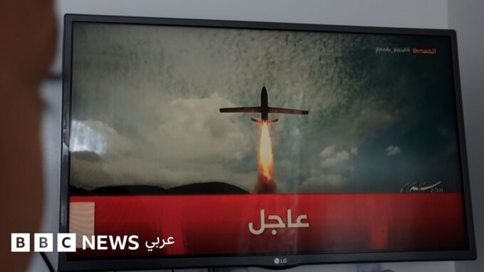 شخص يتابع شاشة تلفزيون تعرض أخبار الصراع بين السعودية والحوثيين في اليمن.