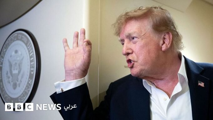 صورة للرئيس الأمريكي دونالد ترامب يتحدث في مؤتمر صحفي مع خلفية علم الولايات المتحدة