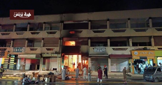 صورة تظهر آثار الحريق المدمر في سوق التقدم (أوبيهي) بمدينة تزنيت، مع وجود فرق الإطفاء
