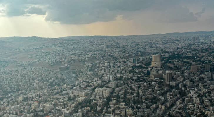 صورة لمدينة عمان تحت سماء غائمة جزئياً مع قطرات مطر خفيفة تعكس الأجواء الخريفية المتوقعة.