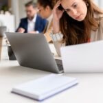 The 'Two-Job Job' Epidemic: Are Companies Trading Efficiency for Employee Burnout? 3 An overwhelmed employee juggling multiple tasks at a desk, symbolizing the 'two-job job' phenomenon.