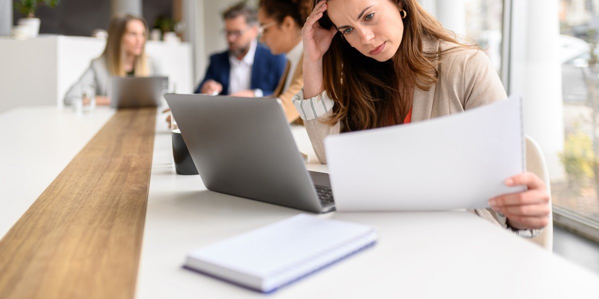 The 'Two-Job Job' Epidemic: Are Companies Trading Efficiency for Employee Burnout? 3 An overwhelmed employee juggling multiple tasks at a desk, symbolizing the 'two-job job' phenomenon.