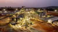 Vue aérienne d'une mine d'or en activité en Afrique de l'Ouest, avec des équipements lourds et des bassins de traitement, symbolisant l'expansion de Fortuna Mining.