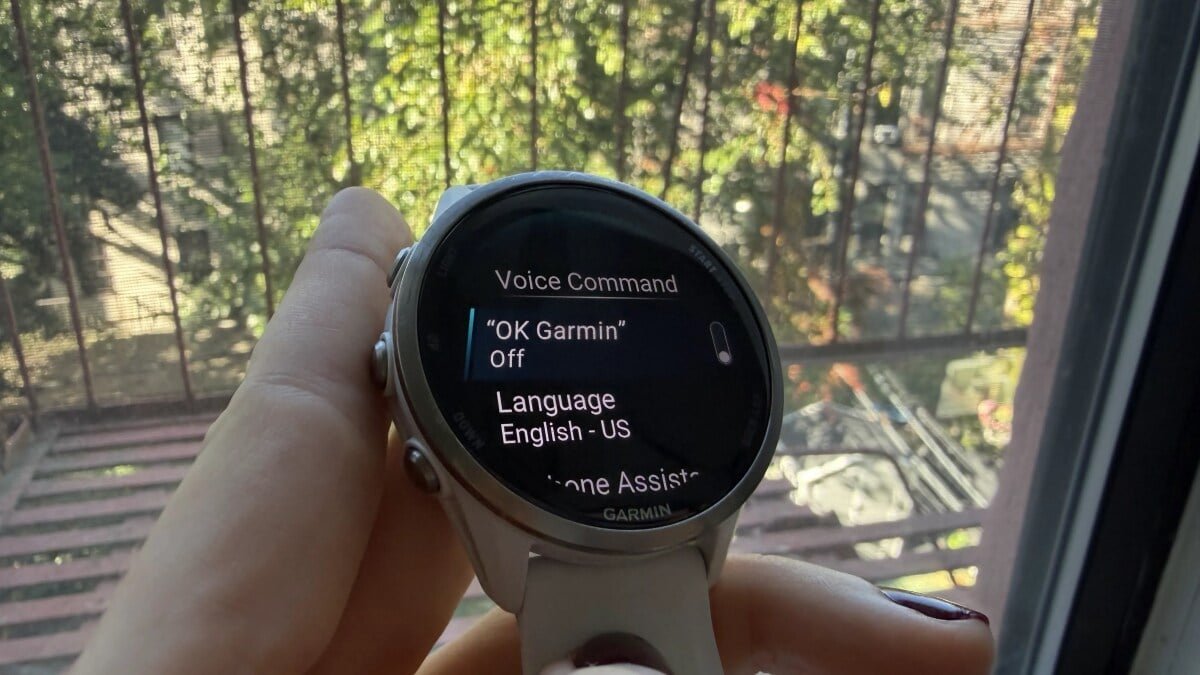 A close-up of a Garmin smartwatch screen displaying battery life, with an overlay indicating the 'OK Garmin' voice assistant feature.