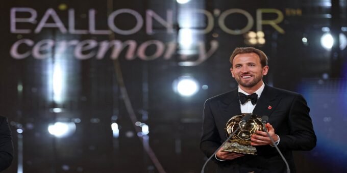 Harry Kane soulevant le Ballon d'Or 2026 lors de la cérémonie à Londres, avec des confettis dorés.