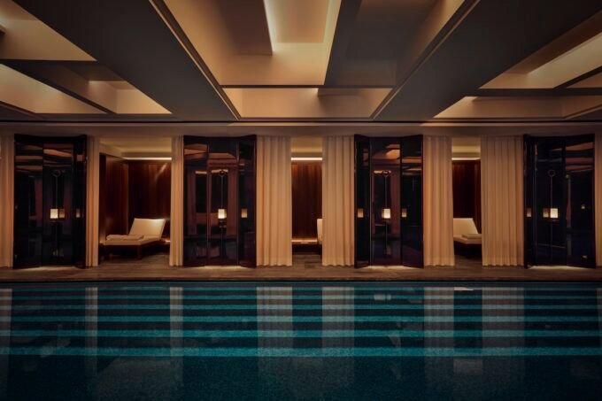 Luxurious swimming pool with lagoon mosaic and curtained lounge nooks at the Hôtel Costes spa, designed by Liaigre.