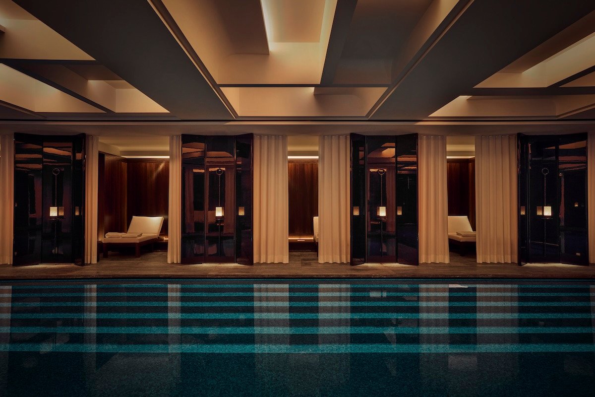 Luxurious swimming pool with lagoon mosaic and curtained lounge nooks at the Hôtel Costes spa, designed by Liaigre.