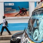 Un panneau publicitaire annonçant les Jeux Olympiques de la Jeunesse de Dakar 2026, avec le slogan 'L’Afrique accueille, Dakar célèbre' et la flamme olympique.