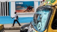 Un panneau publicitaire annonçant les Jeux Olympiques de la Jeunesse de Dakar 2026, avec le slogan 'L’Afrique accueille, Dakar célèbre' et la flamme olympique.
