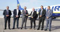 Eddie Wilson, PDG de Ryanair, serrant la main d'un représentant de l'ONMT, avec un avion Ryanair en arrière-plan symbolisant l'expansion au Maroc.
