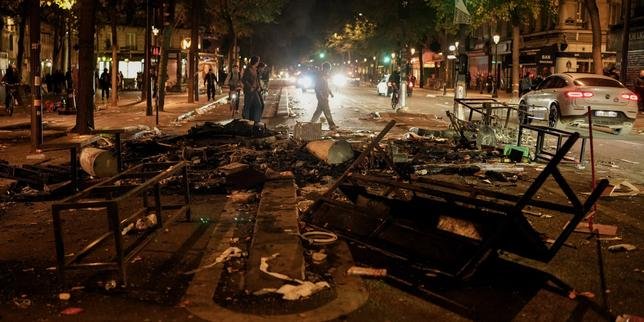 Vue aérienne d'une foule dense de manifestants défilant dans une rue urbaine, avec des drapeaux et des pancartes visibles, sous un ciel couvert, illustrant l'ampleur de la mobilisation du 17 octobre.