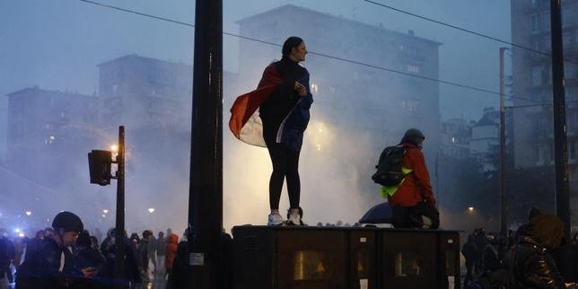 Manifestants défilant dans la rue sous la surveillance des forces de l'ordre lors des manifestations du 24 octobre.