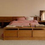 A beautifully curated minimalist bedroom featuring a stylish lamp, a sleek side table, and a comfortable bed, embodying modern serenity.
