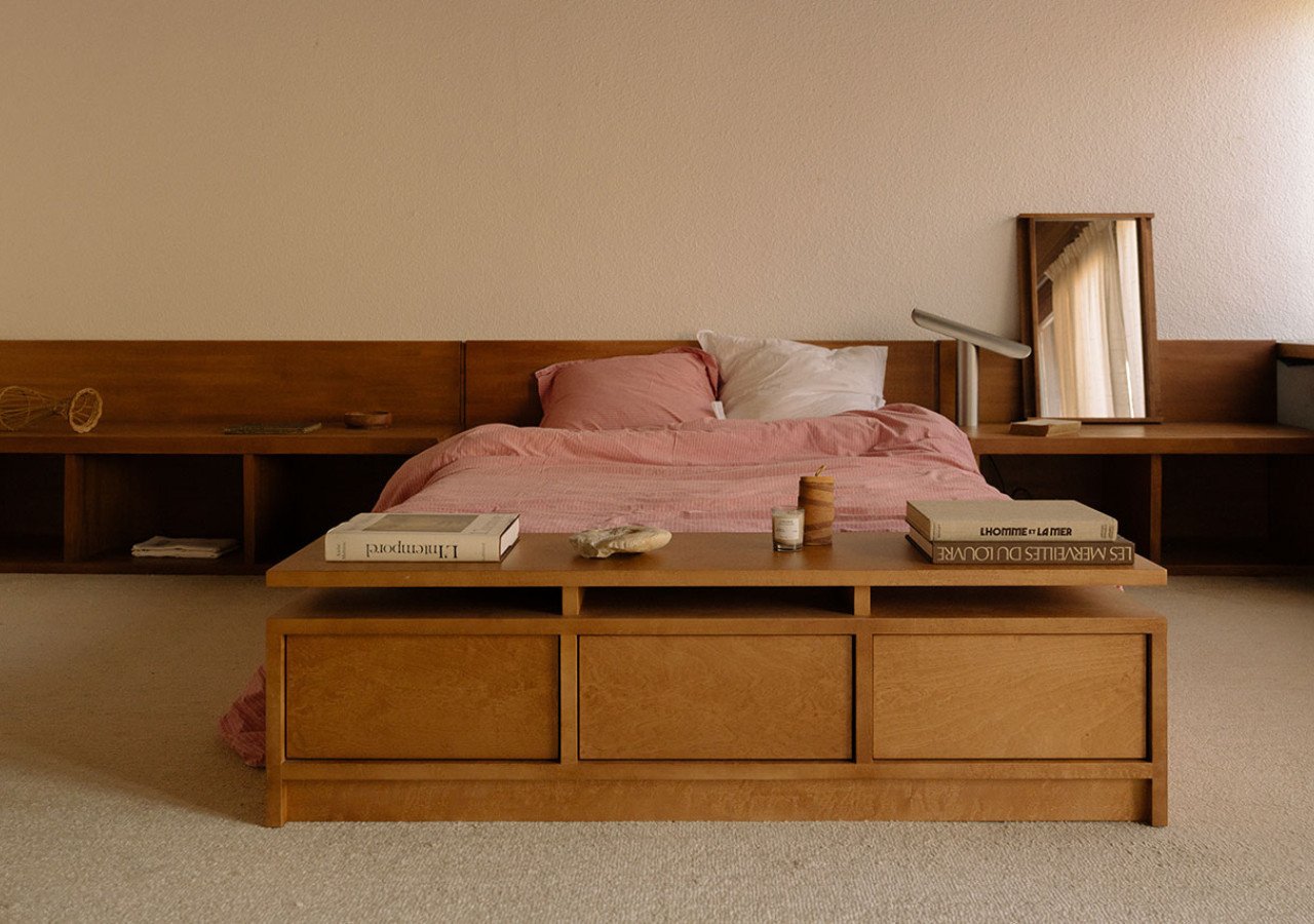 A beautifully curated minimalist bedroom featuring a stylish lamp, a sleek side table, and a comfortable bed, embodying modern serenity.
