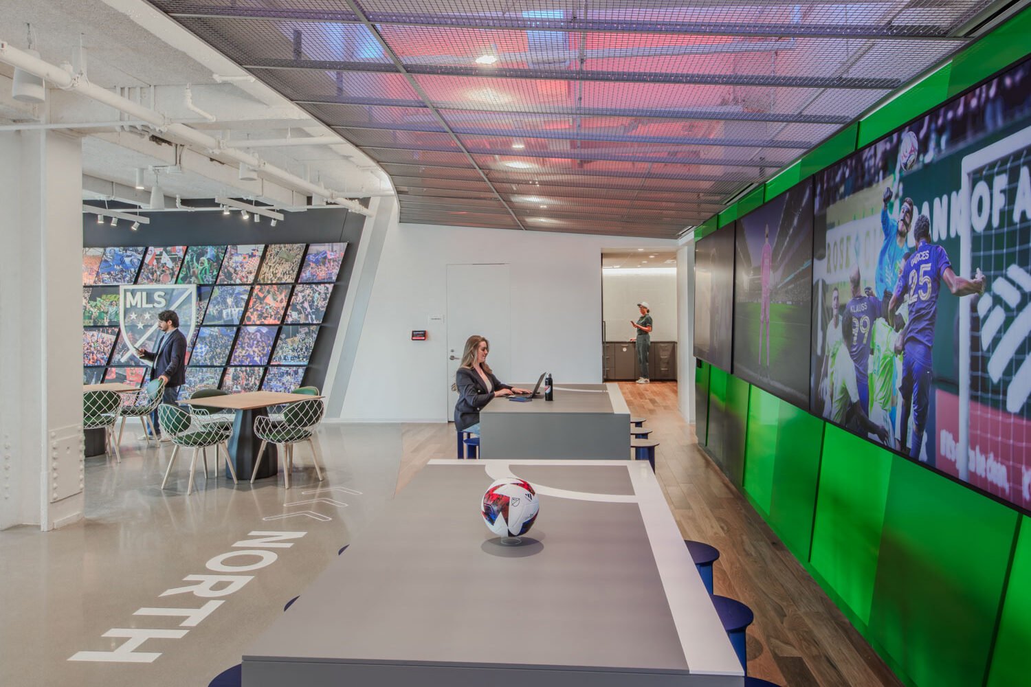 Interior view of the MLS headquarters reception area with club jerseys and the MLS Cup display.
