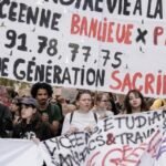 Jeune manifestant lycéen brandissant un drapeau français lors d'un défilé, avec d'autres élèves en arrière-plan et des fumigènes
