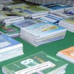 Vue générale du Salon du livre d'Oujda avec des stands, des visiteurs et des livres, sous le thème 'Réinventer un monde en commun'.