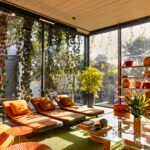 The Paola Lenti São Paulo flagship building, featuring a lush, green living façade of cascading vines over glass and dark metal, with vibrant furniture visible inside.