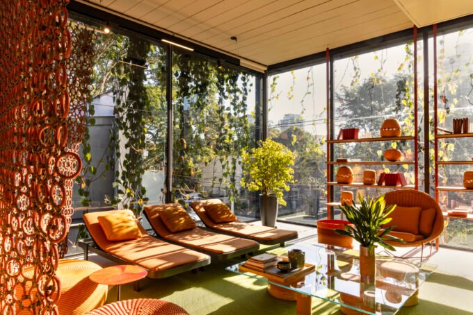 The Paola Lenti São Paulo flagship building, featuring a lush, green living façade of cascading vines over glass and dark metal, with vibrant furniture visible inside.