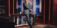 Rich Eisen smiling in a broadcast studio, surrounded by sports media equipment