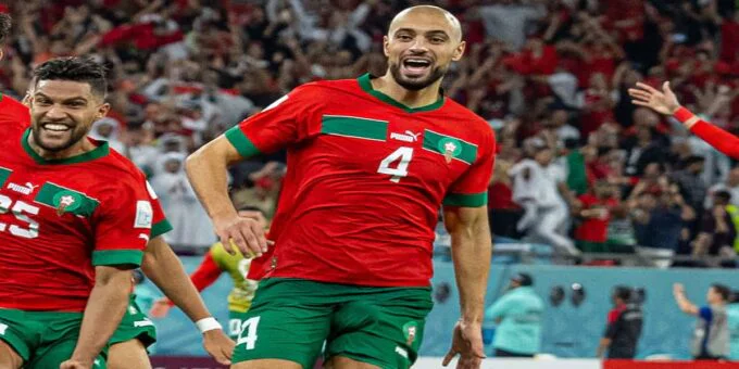Sofyan Amrabat souriant, portant un maillot de football, lors d'une conférence de presse ou d'une séance photo officielle.