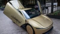 Tesla Cybercab displayed in downtown Austin, Texas, a bronze two-seater driverless vehicle.