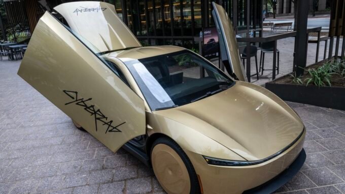 Tesla Cybercab displayed in downtown Austin, Texas, a bronze two-seater driverless vehicle.