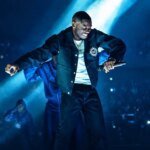 Le rappeur français Tiakola sur scène, micro en main, devant une foule enthousiaste, annonçant son concert au Maroc.