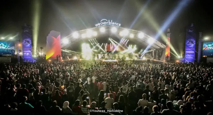Scène de concert en plein air sur la Place Rachidi à Casablanca, avec des artistes en performance et une foule enthousiaste célébrant la Fête de l'Unité.