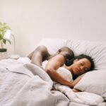 A person peacefully sleeping in bed on a sunny weekend morning, indicating rest and relaxation.
