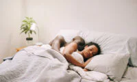 A person peacefully sleeping in bed on a sunny weekend morning, indicating rest and relaxation.