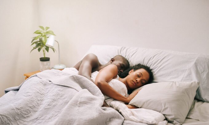 A person peacefully sleeping in bed on a sunny weekend morning, indicating rest and relaxation.